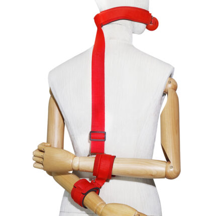 a mannequin wearing a red bondage restraint system. The system includes a collar connected to wrist cuffs via a strap that runs down the back, securing the wearer's hands behind their back. The design emphasizes secure and controlled restraint, suitable for BDSM practices.