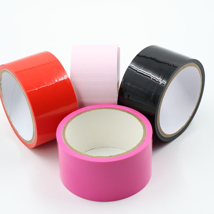 four rolls of adhesive tape in different colors: red, pink, light pink, and black. The tapes are arranged in a visually appealing manner against a white background.