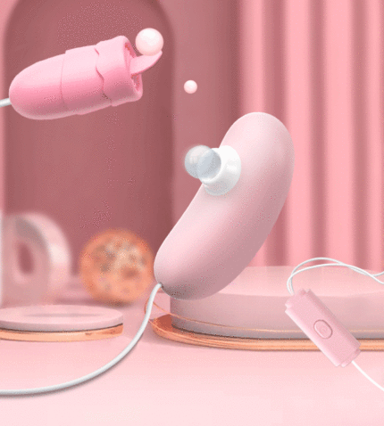 A pink, wired intimate toy set featuring a suction device and a textured vibrator, both with control buttons. The background is a pink setting with various decorative elements, emphasizing the product's design and functionality.