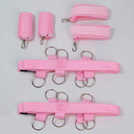 a pink bondage restraint set, which includes wrist and ankle cuffs, as well as connecting straps with metal rings. The set is designed for use in BDSM activities, offering a soft and secure way to restrict movement.