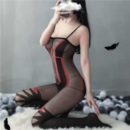 A model is wearing a black mesh bodysuit with red accents and intricate lace patterns. The bodysuit features spaghetti straps and cut-out details on the thighs. The model is kneeling, covering her face, with a playful background of scattered balls and floating feathers.