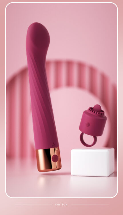 A deep pink vibrator with a gold accent at the base and a textured, slightly curved design. Accompanying it is a small, detachable clitoral stimulator with a ring handle.