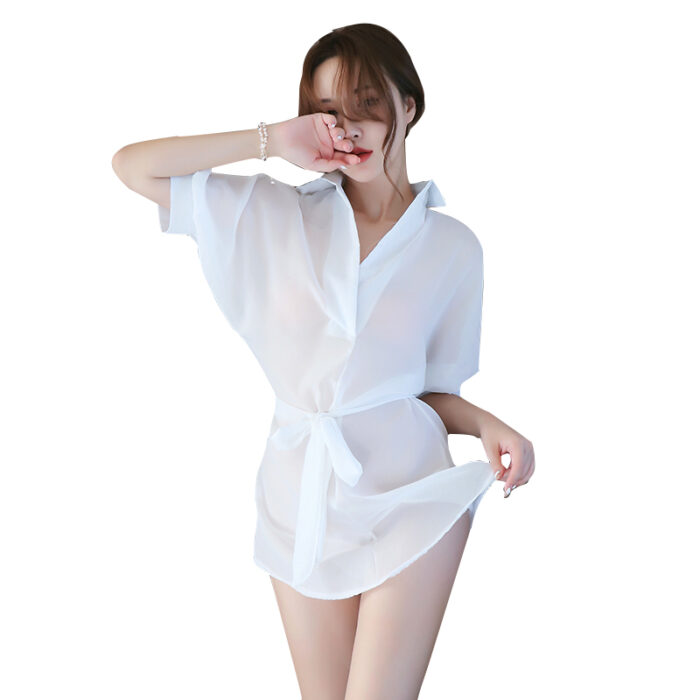 a woman wearing a sheer, white button-up shirt tied at the waist. The shirt is lightweight and semi-transparent, giving it a relaxed and airy look. She appears to be in a casual, playful pose, making the outfit perfect for a beach cover-up or a casual, summer day.