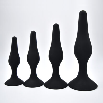 a set of four black silicone anal plugs in different sizes. The plugs have a smooth, tapered design with a flared base for safety and comfort during use. They are intended for use in sexual activities, specifically for anal stimulation. The varying sizes cater to different experience levels and preferences, allowing for gradual progression and comfort.